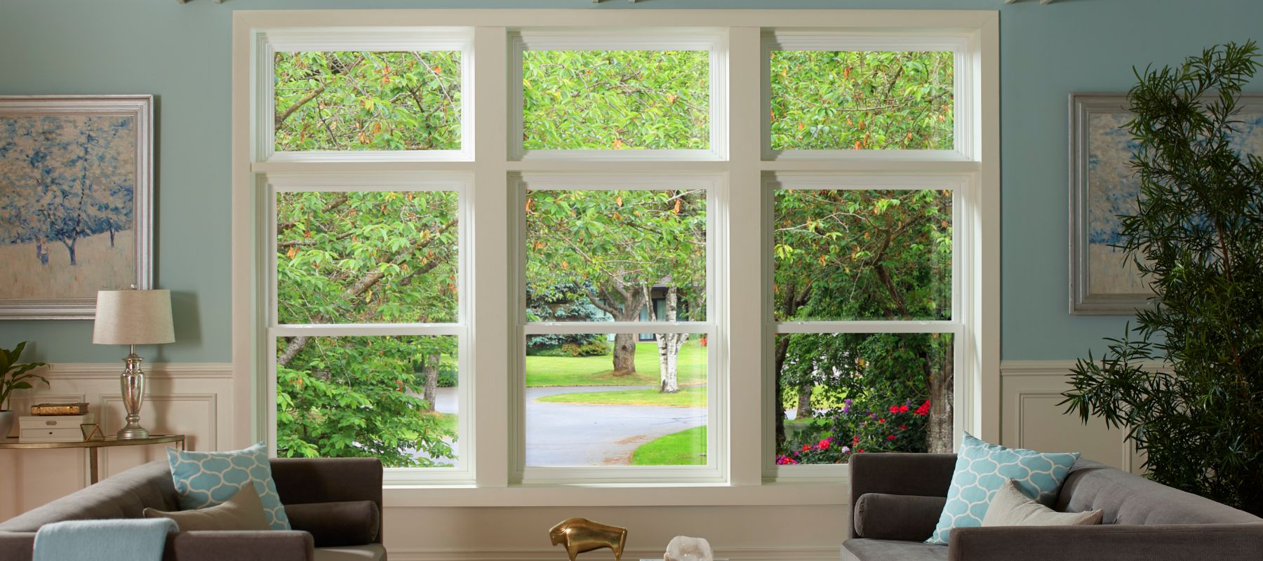 Bright living room with large picture windows showcasing a lush green yard and tree-lined suburban street in Spanish Fort, Alabama