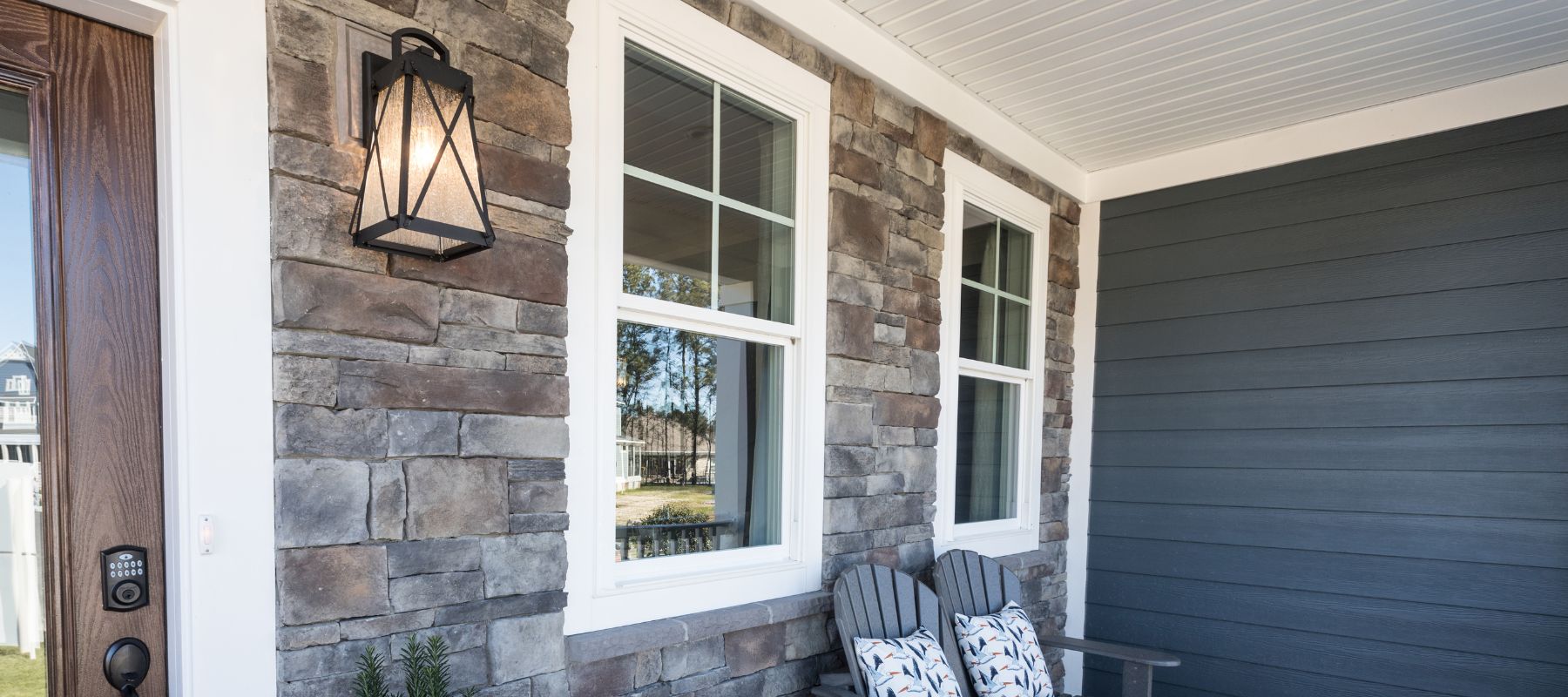 Close-up of a front porch in Elberta, Alabama featuring stone veneer walls, white-trimmed windows, and a decorative lantern light