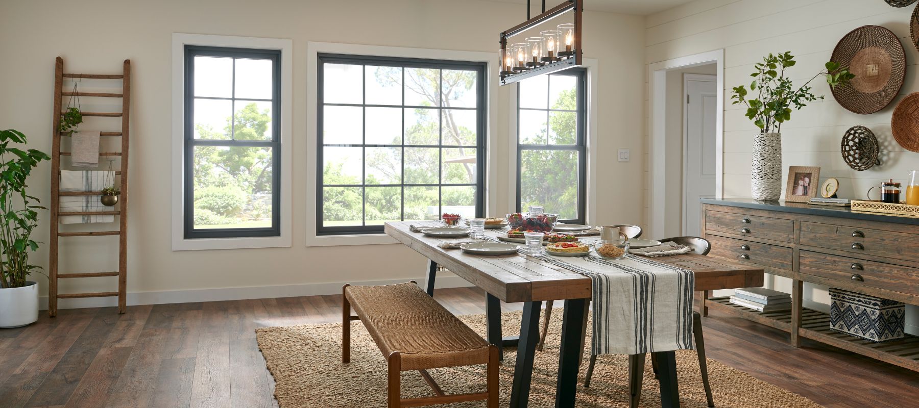 Bright and rustic dining room in a Jackson, Alabama home with large black-trimmed windows and a wood farmhouse table set for a meal